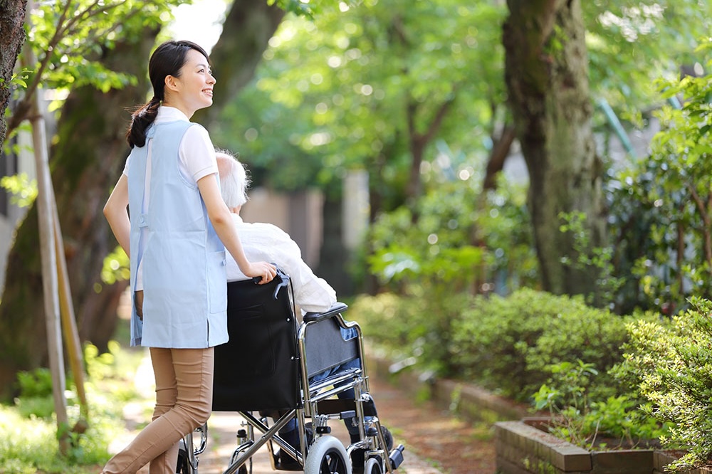 車椅子に乗った入居者をスタッフが押しながら外を散歩する様子